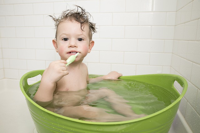 Baby brushing teeth in bath